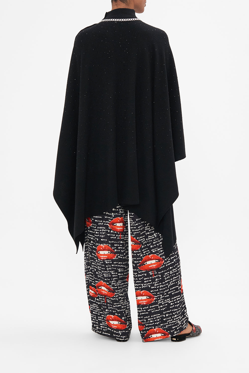 Back view of model wearing CAMILLA black knit poncho in Chaos Magic