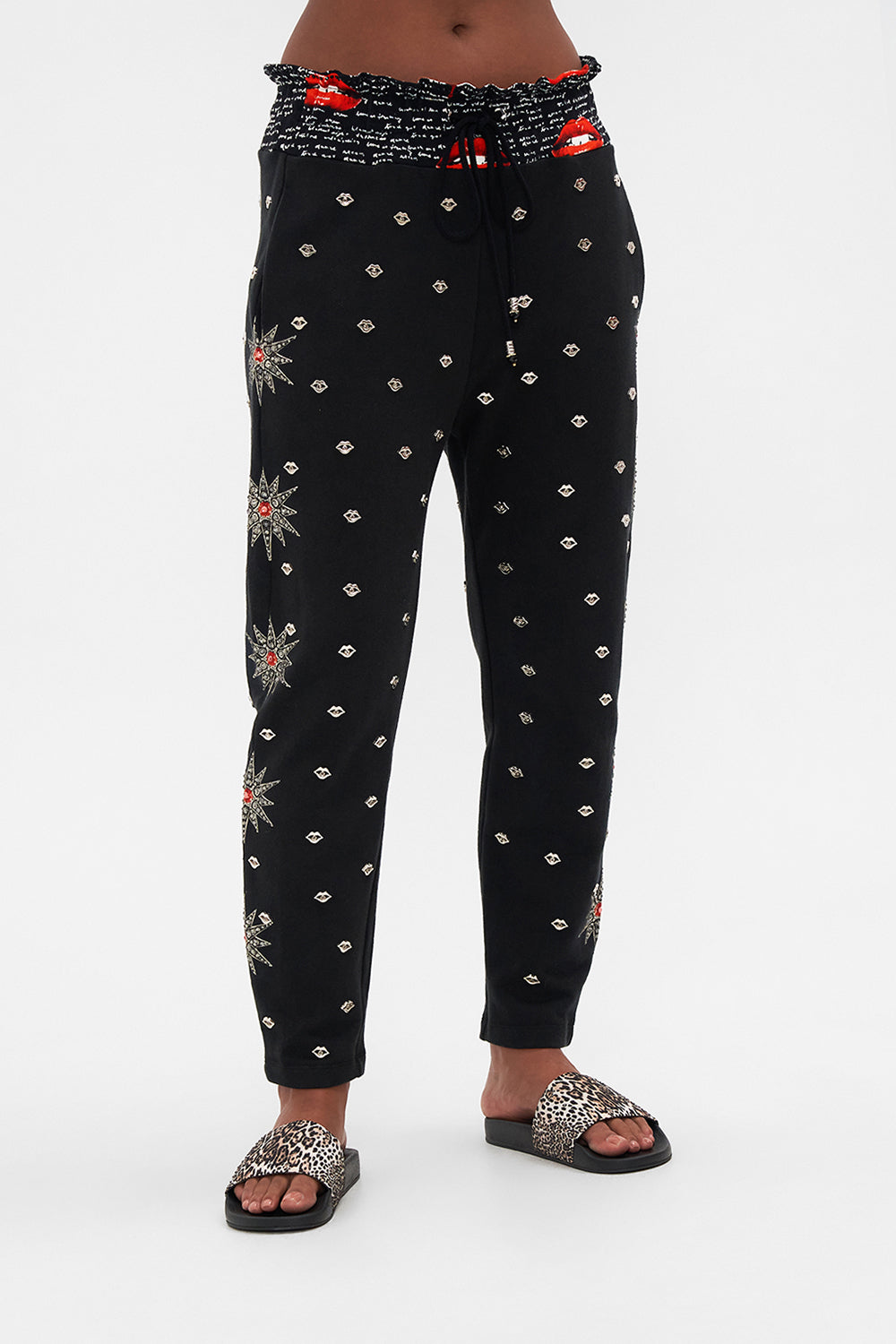 Crop view of model wearing CAMILLA black trackpants in Chaos Magic print