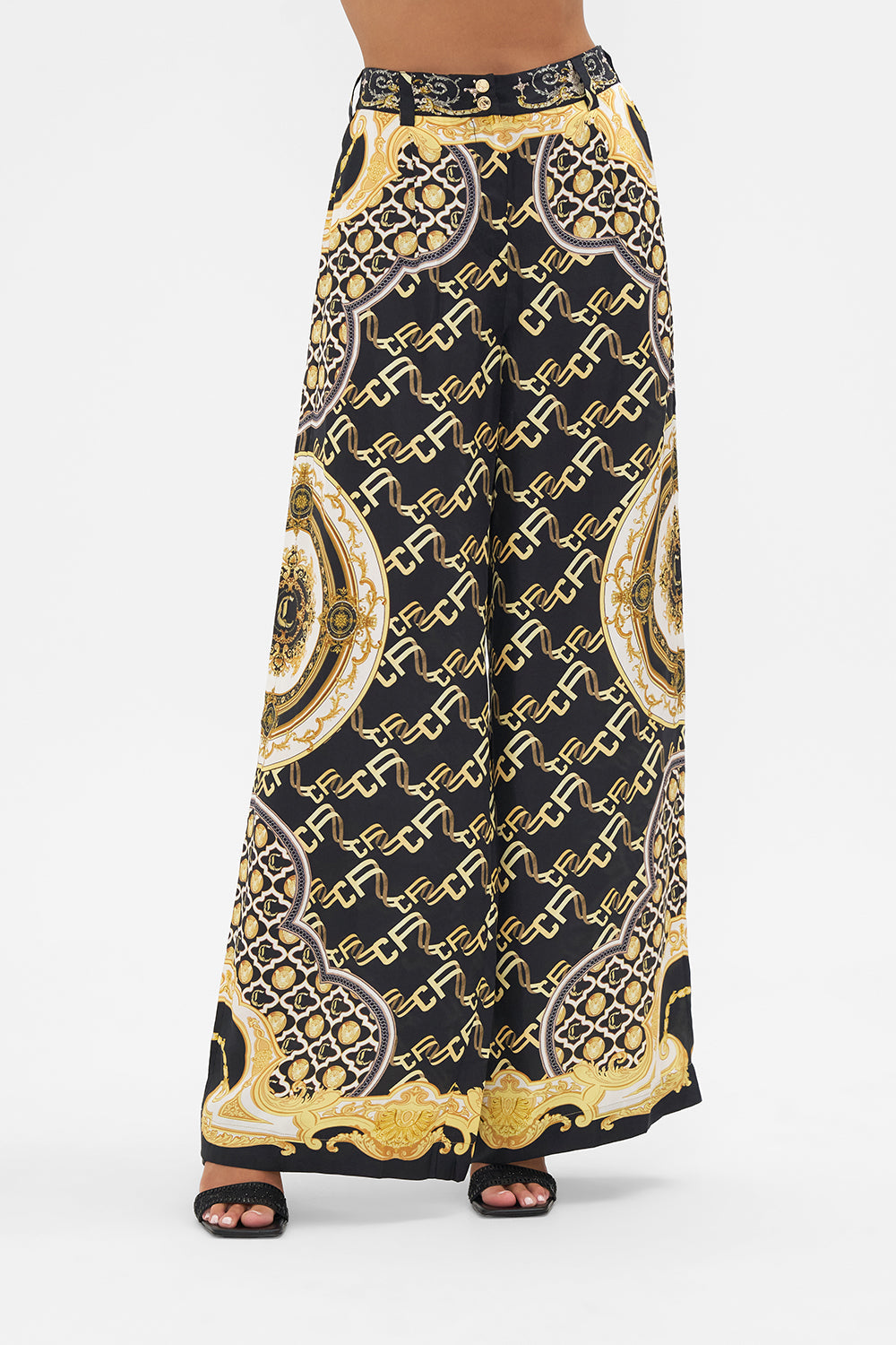 Crop view of model wearing CAMILLA black silk pants in Tether Me Not print