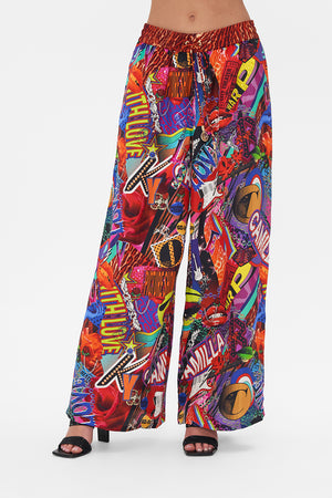Crop view of model wearing CAMILLA silk palazzo pants in multicoloured Radical Rebirth print