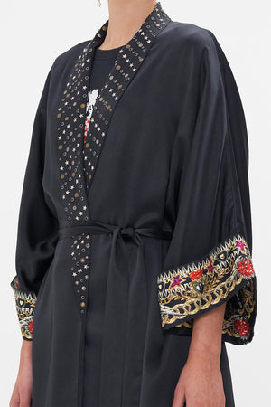 Crop view of model wearing CAMILLA black silk robe in Radical Rebirth print