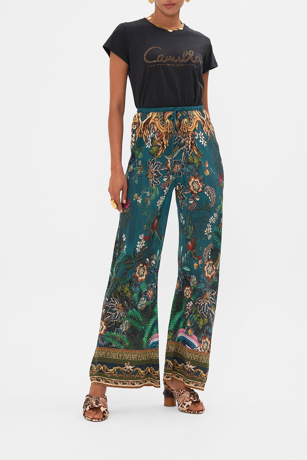 Front view of model wearing CAMILLA green silk pants in Verdis World print
