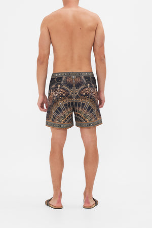Back view of model wearing hotel franks By CAMILLA mens boardshort in Masked At Moonlight print