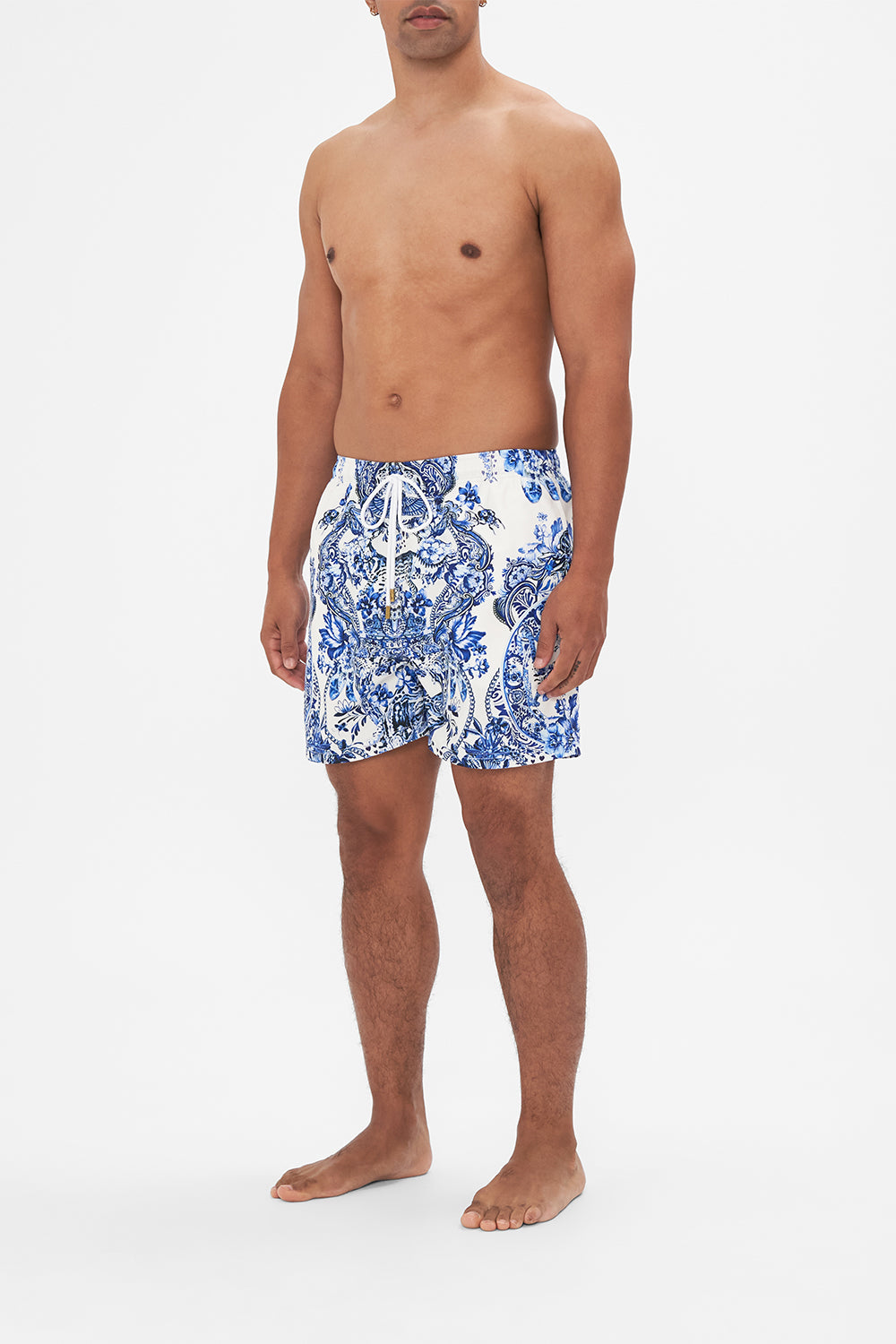 Side view of model wearing Hotel Franks By CAMILLA blue and white mens boardshorts in Glaze and Graze print