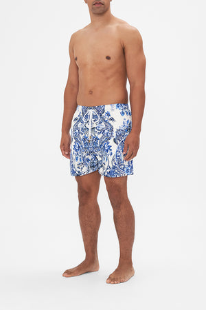 Side view of model wearing Hotel Franks By CAMILLA blue and white mens boardshorts in Glaze and Graze print