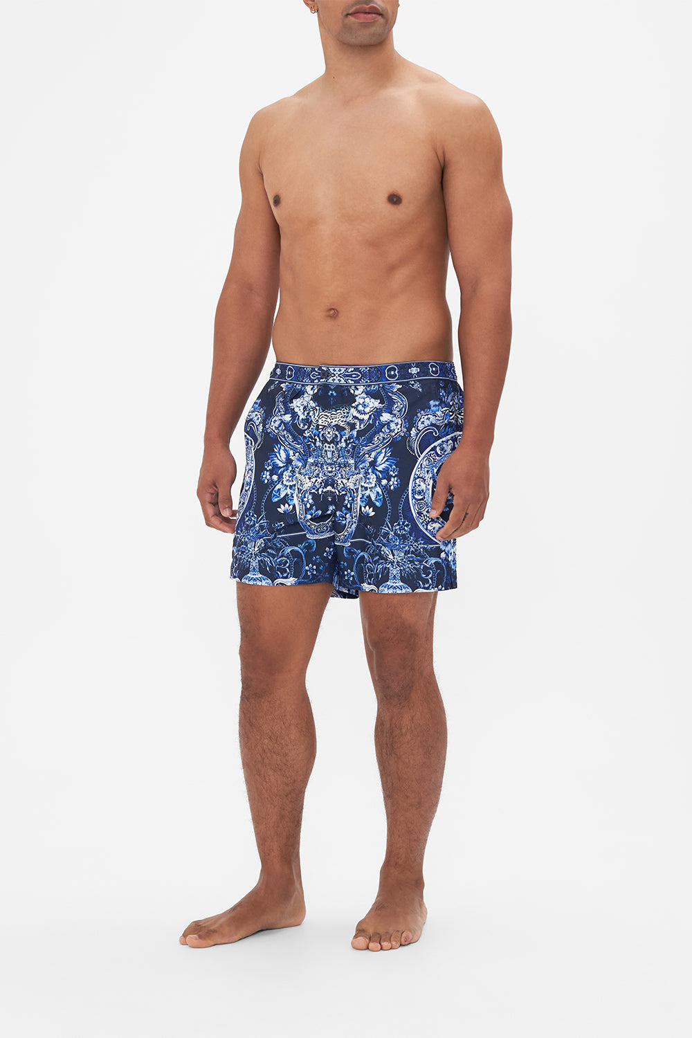 Side view of model wearing Hotel Franks By CAMILLA mens blue swim shorts in Delft Dynasty print