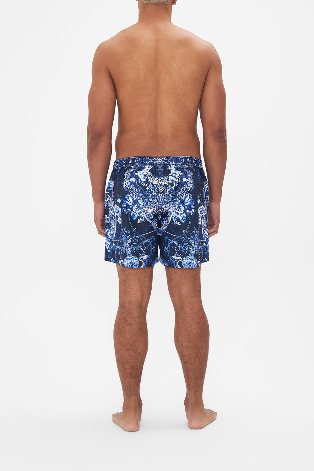 Back view of model wearing Hotel Franks By CAMILLA mens blue swim shorts in Delft Dynasty print