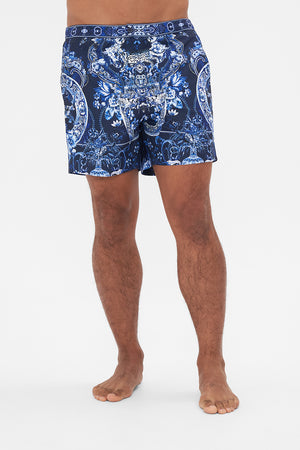 Crop view of model wearing Hotel Franks By CAMILLA mens blue swim shorts in Delft Dynasty print