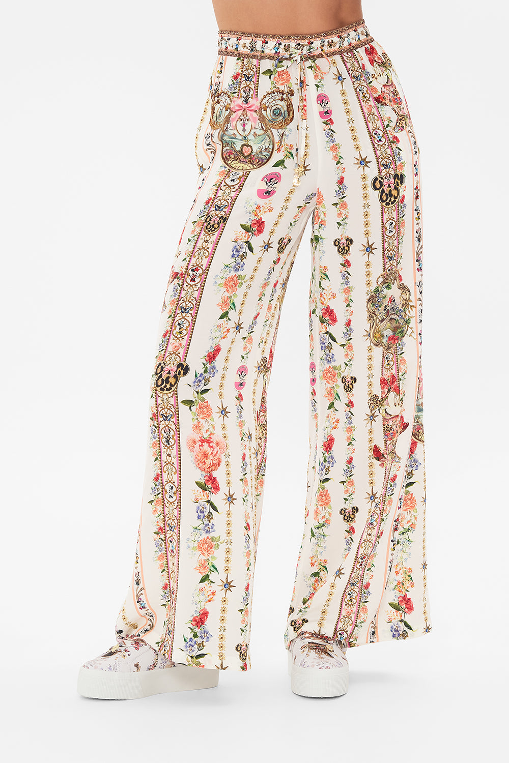 Crop view of model wearing Disney x CAMILLA silk pants in Minnie Magic Forever print