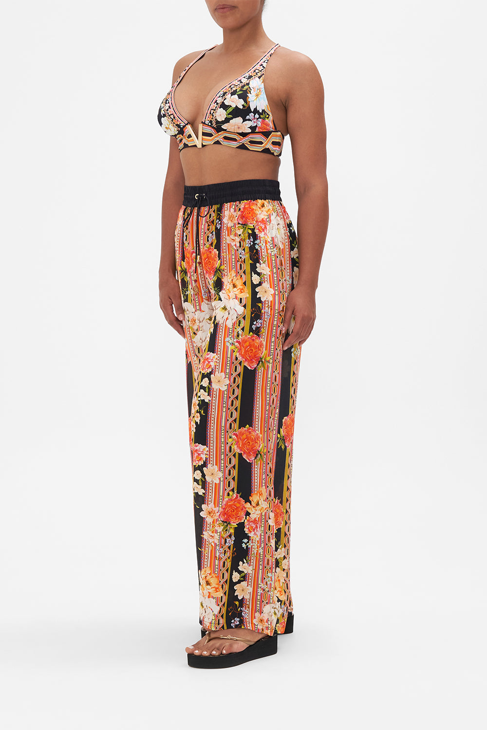 Side view of model wearing CAMILLA floral silk pants in Secret History print