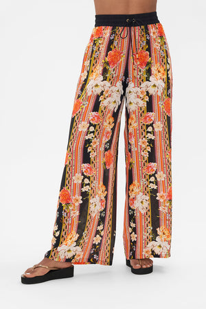Crop view of model wearing CAMILLA floral silk pants in Secret History print