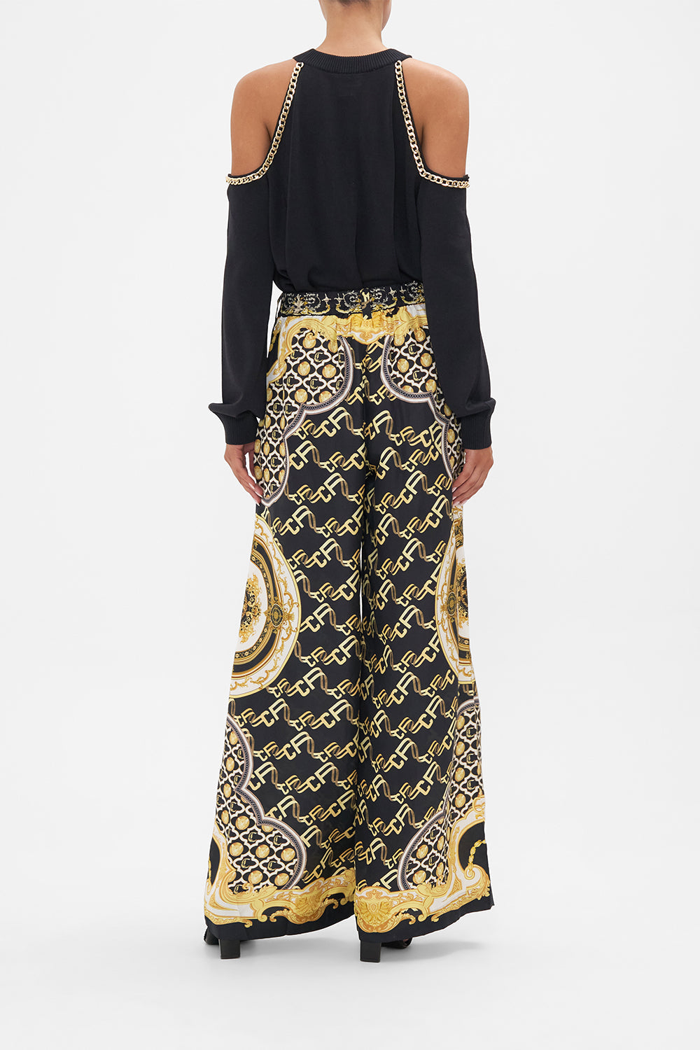 Back view of model wearing CAMILLA black silk pants in Tether Me Not print